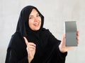 Cheerful young muslim woman dressed in black hijab showing off new phone