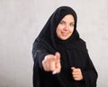 Cheerful young muslim woman dressed in black hijab pointing at side