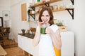 Smiling young woman drinking green smoothie juice in kitchen. Royalty Free Stock Photo