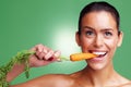 Smiling young woman eating carrot against green background. Closeup portrait of a smiling young woman eating carrot Royalty Free Stock Photo