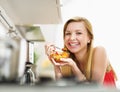 Smiling young woman eating fresh fruits salad in kitchen Royalty Free Stock Photo