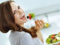 Smiling young woman eating fresh salad in kitchen Royalty Free Stock Photo