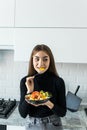 Smiling young woman eating fresh salad in modern kitchen Royalty Free Stock Photo