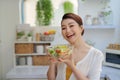 Smiling young woman eating fresh salad in modern kitchen Royalty Free Stock Photo