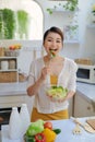 Smiling young woman eating fresh salad in modern kitchen Royalty Free Stock Photo