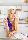 Smiling young woman eating fruits salad in kitchen Royalty Free Stock Photo