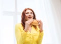 Smiling young woman eating hamburger at home