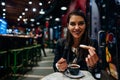 Smiling young woman eating traditional spanish churros with sugar dipped in hot chocolate sauce in a original spanish style cafe.