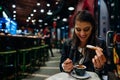 Smiling young woman eating traditional spanish churros with sugar dipped in hot chocolate sauce in a original spanish style cafe.