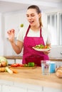 Smiling young woman eating vegetable salad in home kitchen Royalty Free Stock Photo