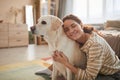 Smiling Young Woman Embracing Dog at Home in Sunlight Royalty Free Stock Photo