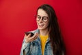 Smiling young woman in eyeglasses holding phone speak activate virtual digital voice recognition assistant on smartphone Royalty Free Stock Photo