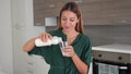 Smiling young woman fills glass of kefir in the kitchen of her home