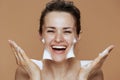 smiling young woman with foaming facial cleanser washing face