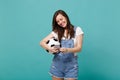 Smiling young woman football fan with soccer ball using mobile phone, typing sms message isolated on blue turquoise wall Royalty Free Stock Photo