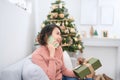 Smiling young woman with gift box talking on a smartphone near Christmas tree Royalty Free Stock Photo