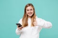 Smiling young woman girl in casual white hoodie posing isolated on blue turquoise wall background studio portrait Royalty Free Stock Photo