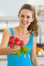 Smiling young woman giving bunch of radishes