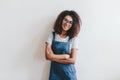 Smiling young woman in glasses with dark-brown hair posing with arms crossed in front of light wall. Portrait of Royalty Free Stock Photo