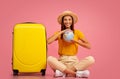 Smiling young woman with globe sitting next to luggage Royalty Free Stock Photo