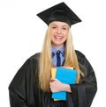 Smiling young woman in graduation gown with books Royalty Free Stock Photo