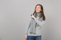 Smiling young woman in gray sweater, scarf looking up, pointing index finger aside on grey wall background Royalty Free Stock Photo