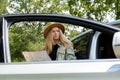 Smiling young woman in hat stoped on road to check the route on travel map. Local solo travel on weekends concept Royalty Free Stock Photo