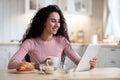 Smiling Young Woman Having Breakfast And Using Digital Tablet In Kitchen Royalty Free Stock Photo