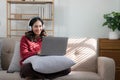 Smiling young woman with headphones using laptop in livingroom. Female studying at home. Young woman wearing headphones Royalty Free Stock Photo
