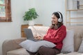 Smiling young woman with headphones using laptop in livingroom. Female studying at home. Young woman wearing headphones Royalty Free Stock Photo