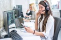 Smiling young woman with headset using phone in office. Royalty Free Stock Photo