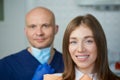 A smiling young woman with her bald middle-aged dentist in a dentist`s office Royalty Free Stock Photo