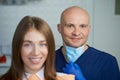 A smiling young woman with her bald middle-aged dentist in a dentist`s office Royalty Free Stock Photo