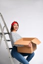 Pretty woman standing on light background with moving cardboard box