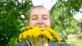 Smiling woman holding floral bouquet of dandelions. woman and yellow wildflowers