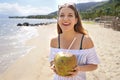 Smiling young woman holding green coconut on tropical beach. Summer vacation concept Royalty Free Stock Photo