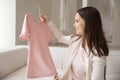 Smiling young woman holding hanger with t-shirt, unpacking store order Royalty Free Stock Photo