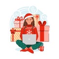 Smiling young woman holding a laptop with gifts on background. Girl wearing a scandinavian sweater and a Santa hat. Online Royalty Free Stock Photo