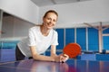 Smiling young woman holding racket in hand leaning over tennis table Royalty Free Stock Photo