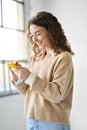 Smiling young woman using mobile cell phone indoors, vertical. Royalty Free Stock Photo