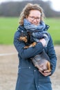 A smiling young woman holds a pregnant Jack russel terier in her arms. The dog`s big belly can be seen clearly. Outside in the Royalty Free Stock Photo