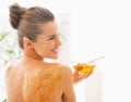 Smiling young woman with honey plate sitting on massage table Royalty Free Stock Photo