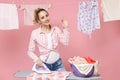 Smiling young woman housewife in checkered shirt dry clothes on rope ironing clean clothes on board while doing Royalty Free Stock Photo