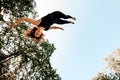 Smiling young woman jumping and tumbling in the air against the blue sky. Royalty Free Stock Photo