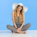 Smiling Young Woman In Jumpsuit, White Sun Hat And High Heels Is Sitting With Legs Crossed Royalty Free Stock Photo