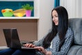 Smiling young woman laying on couch and using laptop Royalty Free Stock Photo