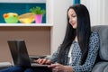 Smiling young woman laying on couch and using laptop Royalty Free Stock Photo