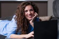 Smiling young woman laying on couch and using laptop. Royalty Free Stock Photo