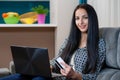 Smiling young woman laying on couch and using laptop Royalty Free Stock Photo