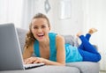 Smiling young woman laying on sofa and using laptop Royalty Free Stock Photo